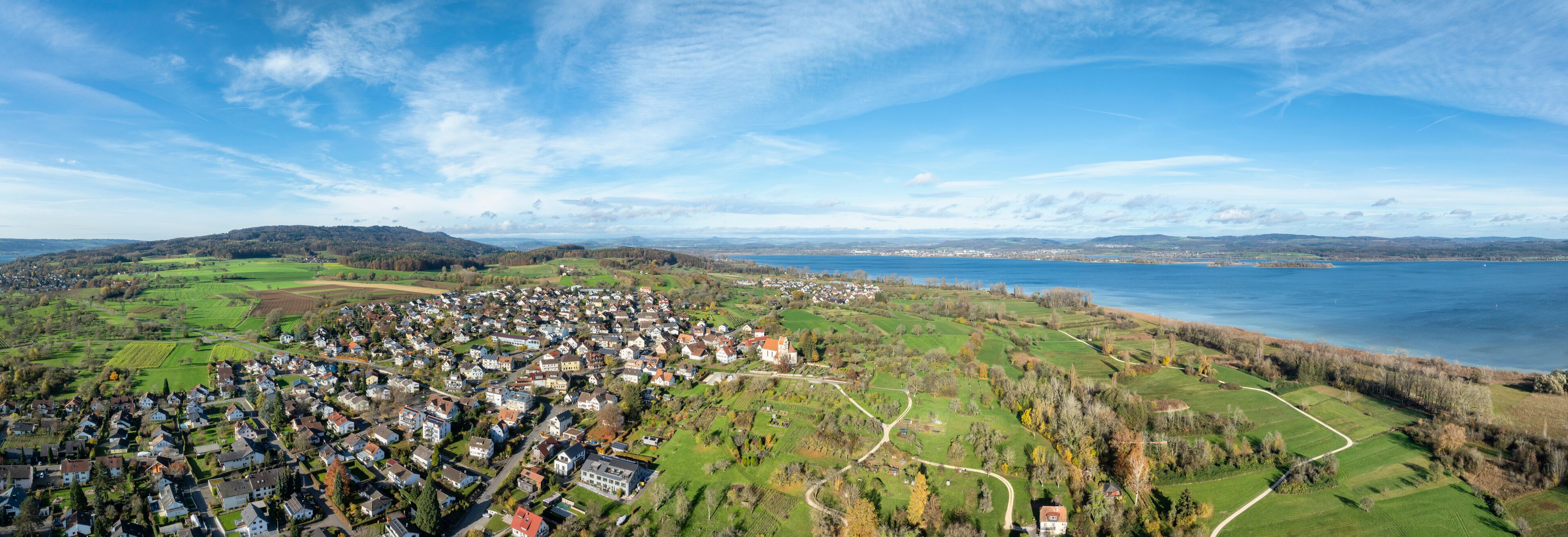 A coastal town with houses, green fields, and a lake.