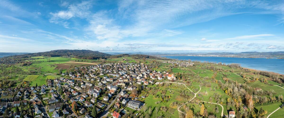 A coastal town with houses, green fields, and a lake.