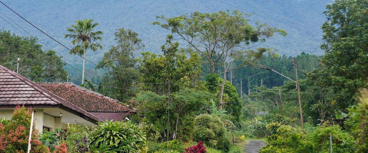 A mountain with a cloud base, surrounded by lush greenery and residential buildings.