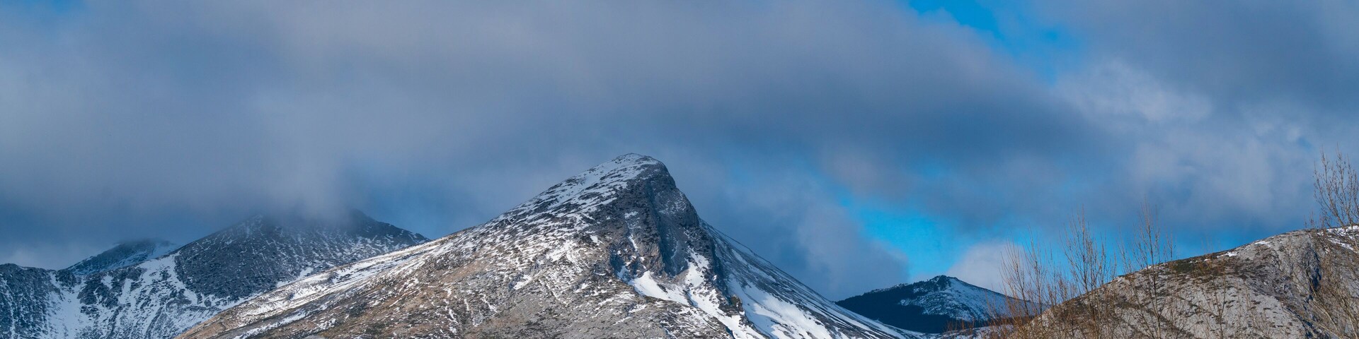 A snow-capped mountain range with a clear sky and some clouds.