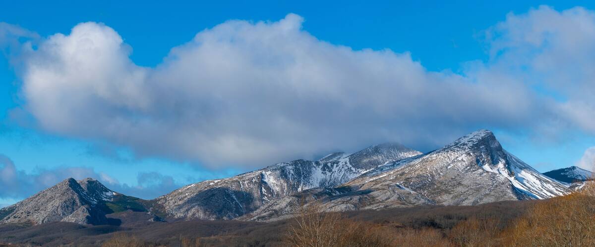 A mountain range with snow-capped peaks under a clear blue sky.