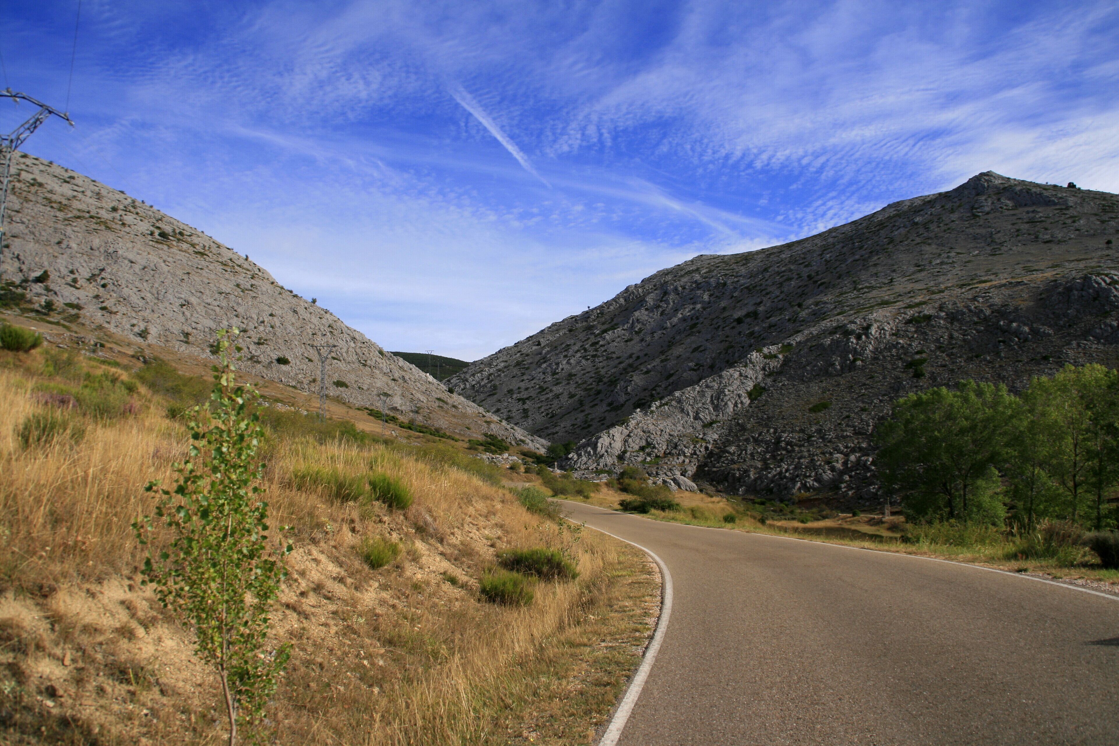 A winding mountain road with rocky terrain and sparse vegetation.