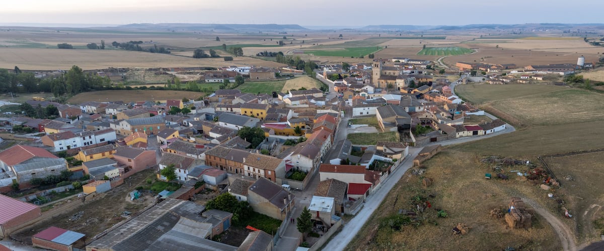 An aerial view of a small town with colorful houses, a church, and surrounding fields.