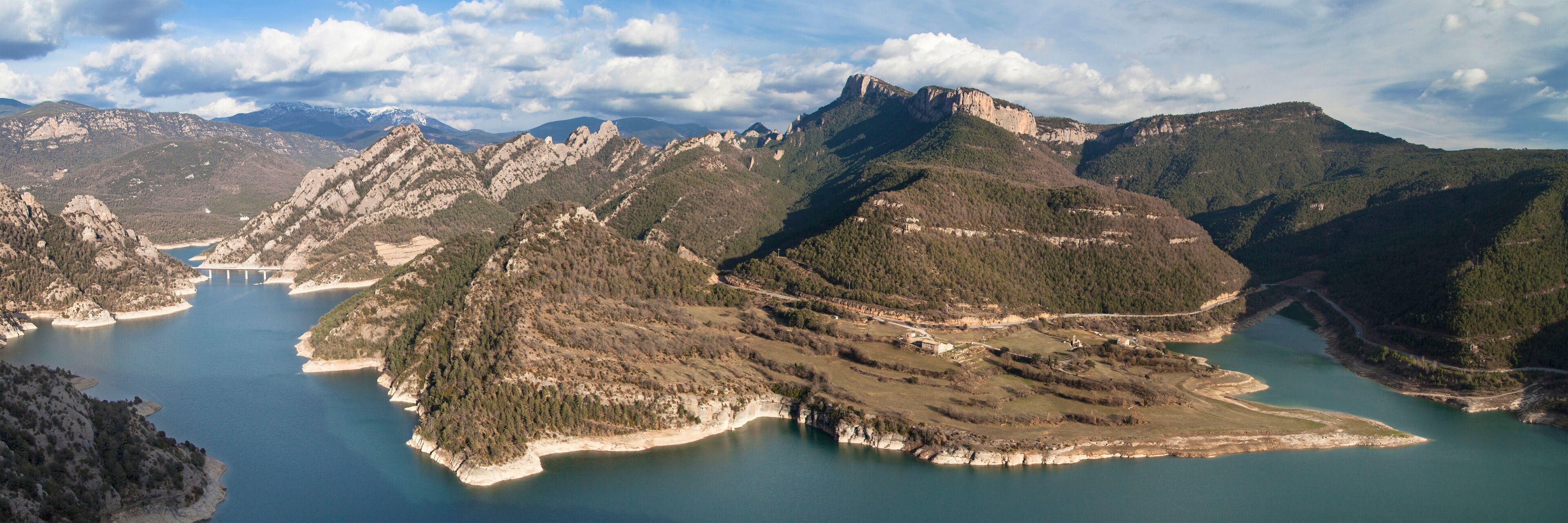 A mountainous landscape with a lake and a bridge.