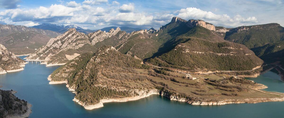 A mountainous landscape with a lake and a bridge.