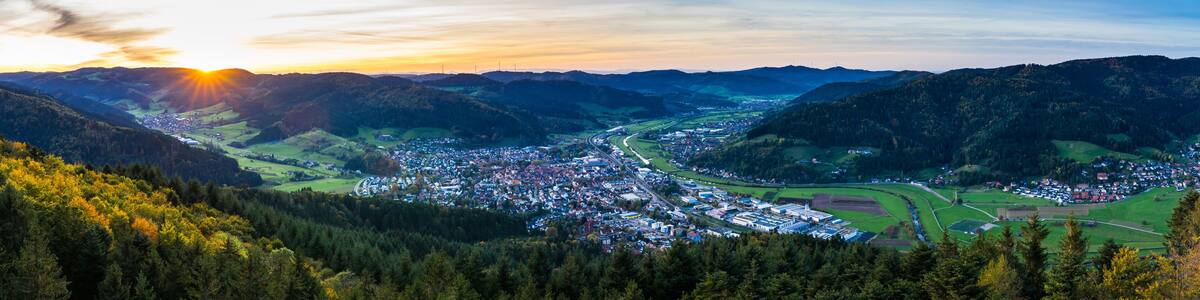 Germany, XXL aerial panorama view above black forest village haslach im kinzigtal and endless nature landscape over tree tops at sunset in autumn season