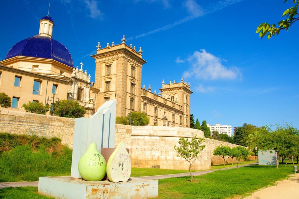 A historic building with a blue dome and a tower, surrounded by greenery and a clear sky.