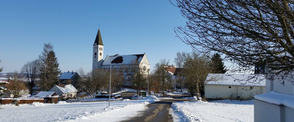 A snow-covered street leading to a church with a tall tower.
