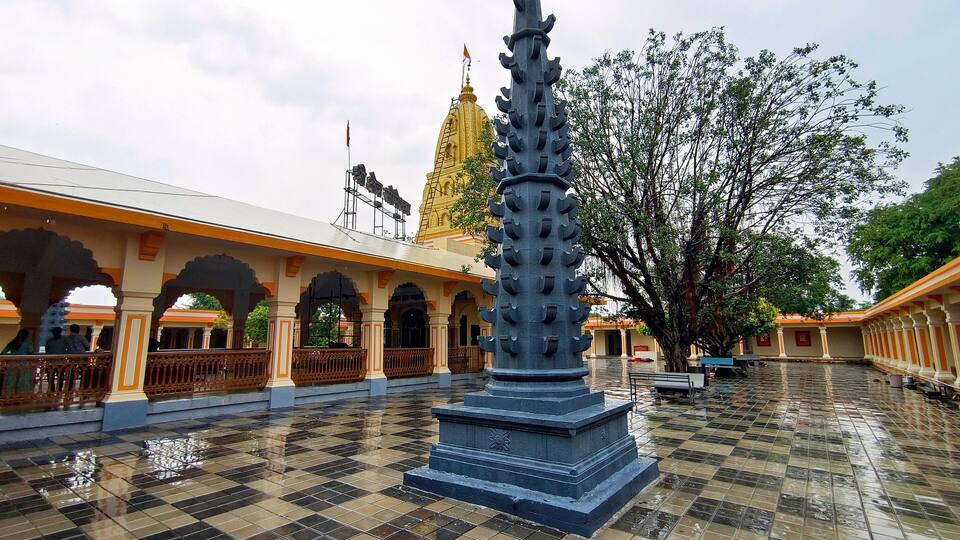 A tiled courtyard with a central statue, arches, and a large tree.