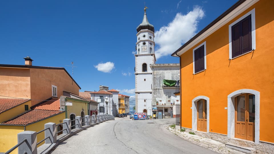 A street leading to a church with a bell tower, surrounded by colorful buildings.