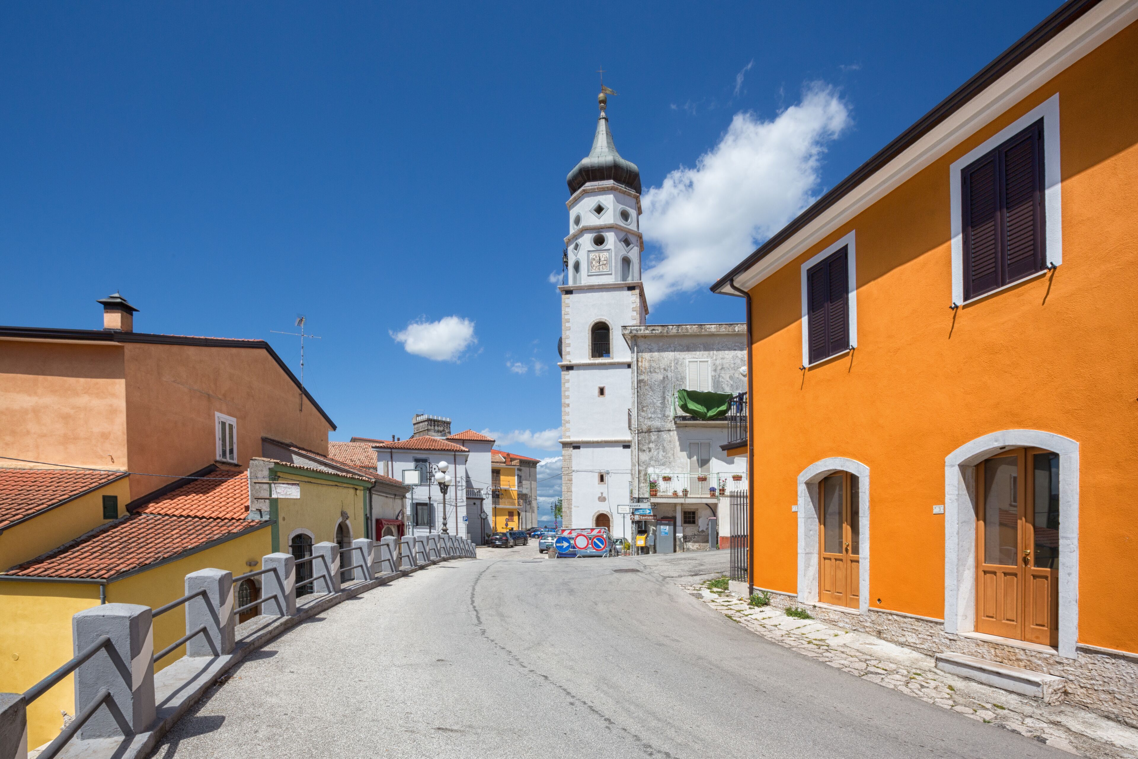 A street leading to a church with a bell tower, surrounded by colorful buildings.