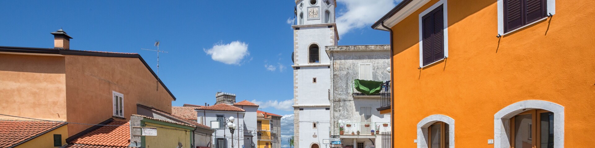 A street leading to a church with a bell tower, surrounded by colorful buildings.