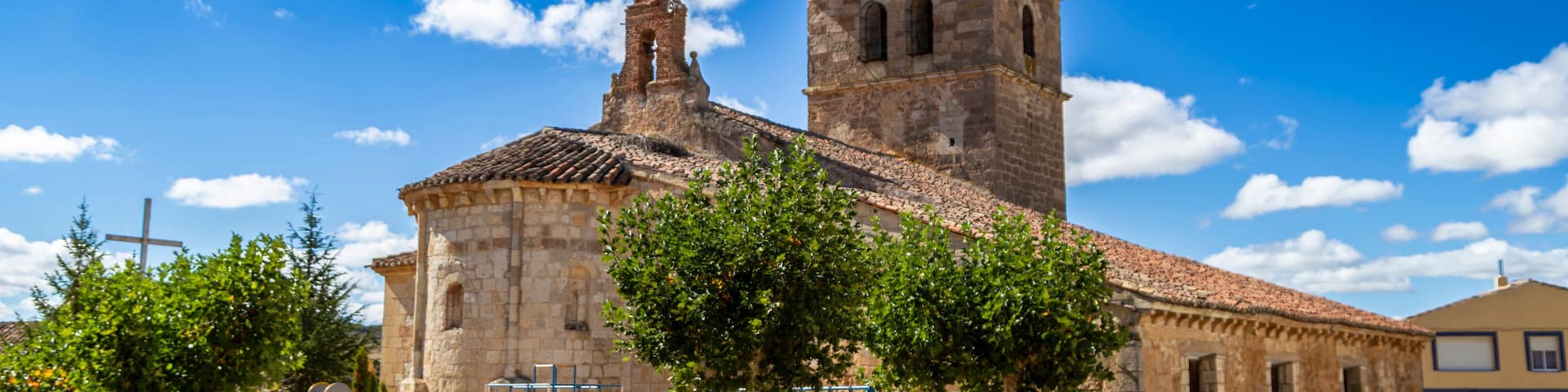 The ancient Church of Nuestra Señora de la Asunción alongside a children's playground in Villabermudo, Palencia, Spain