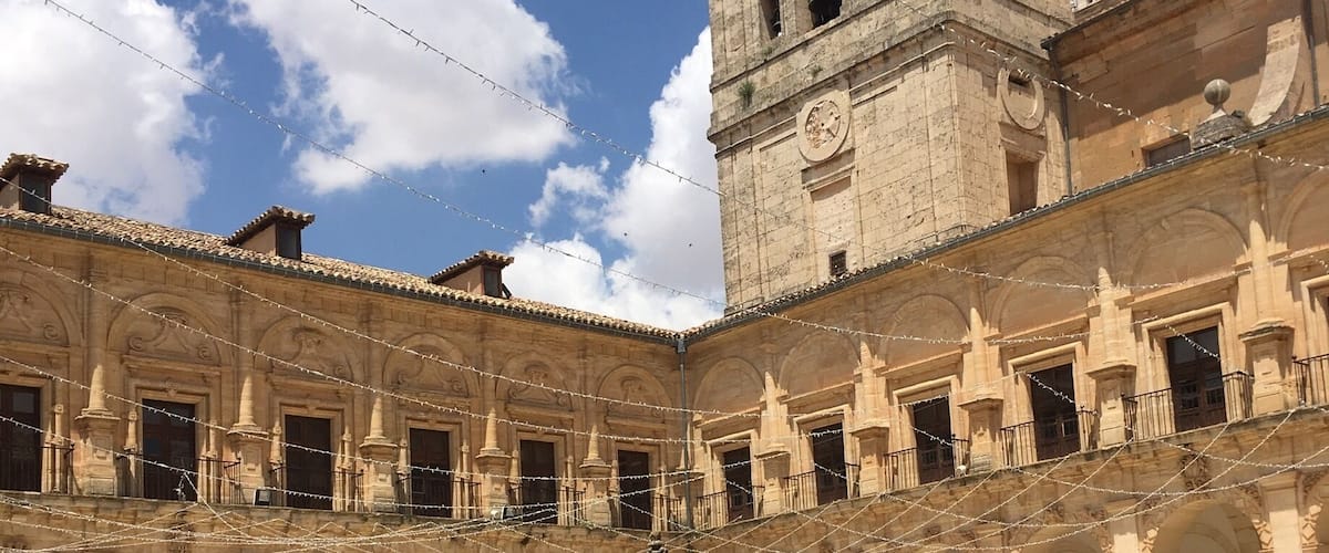 A courtyard with a central fountain, surrounded by arches and a bell tower.