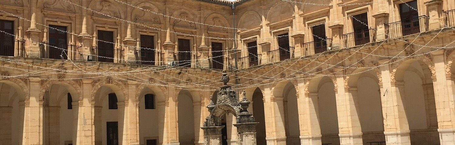 A courtyard with a central fountain, surrounded by arches and a bell tower.