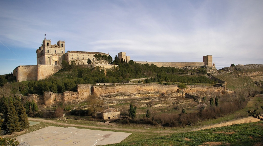Vista del Monasterio de Uclés en la cima del cerro de El Portillo. Fue construido entre el siglo XVI y XVII sobre los restos del castillo musulmán (a la derecha del castillo). Debido al largo periodo de construcción tiene elementos platerescos, herrerianos y churrigueresco. Fue construido por la Orden de Santiago cuya casa central (Caput Ordinis) se encontraba allí. Para su construcción se utilizaron materiales de la antigua ciudad romana de Segobriga.