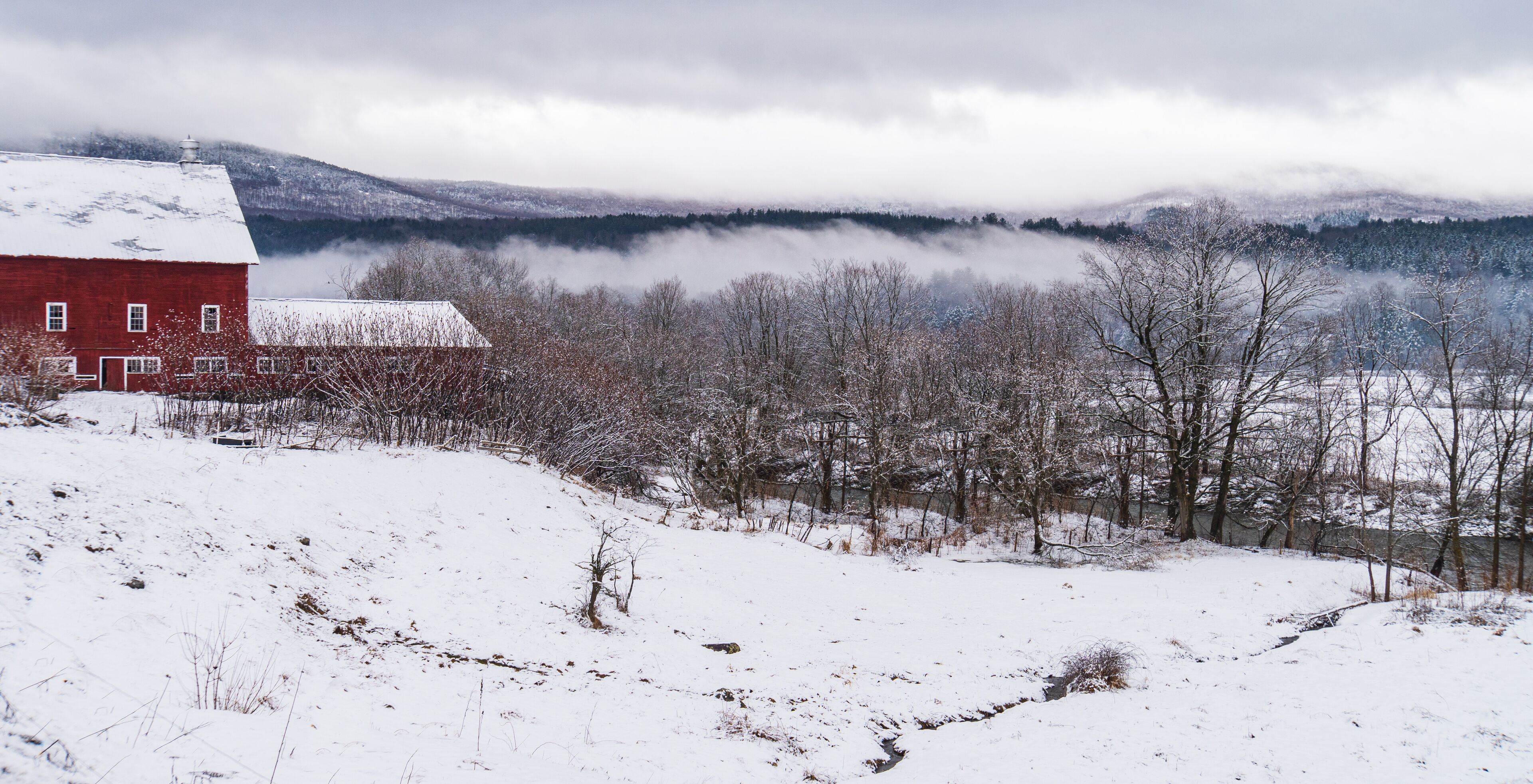farm with red barn overlooking river in rural Vermont, New England
