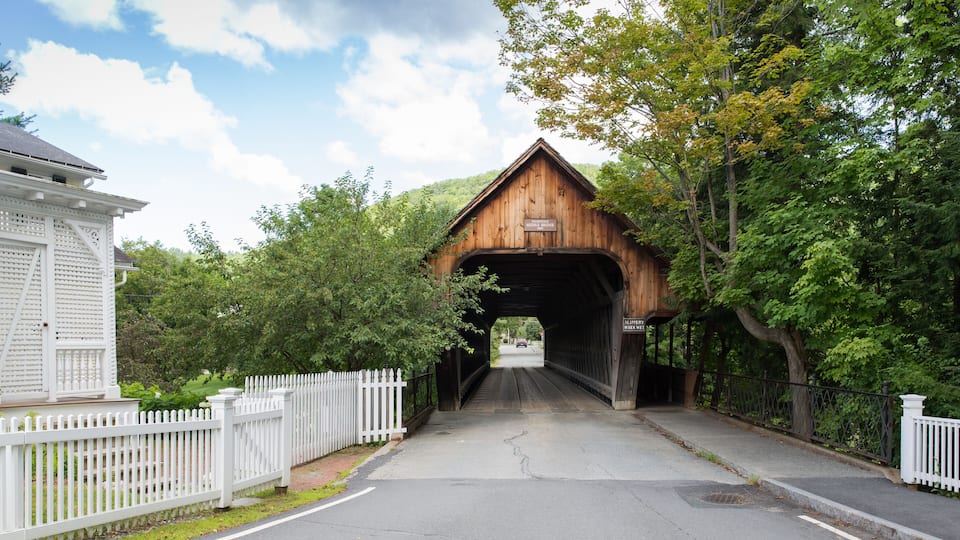 A covered wooden bridge with a sign reading "Slippery When Wet."