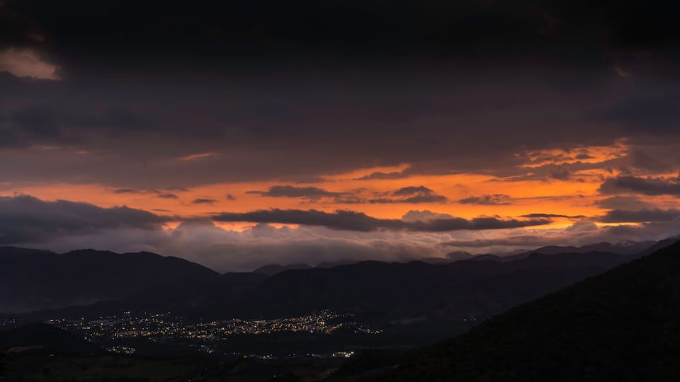 A mountain range at dusk with a city in the valley below.