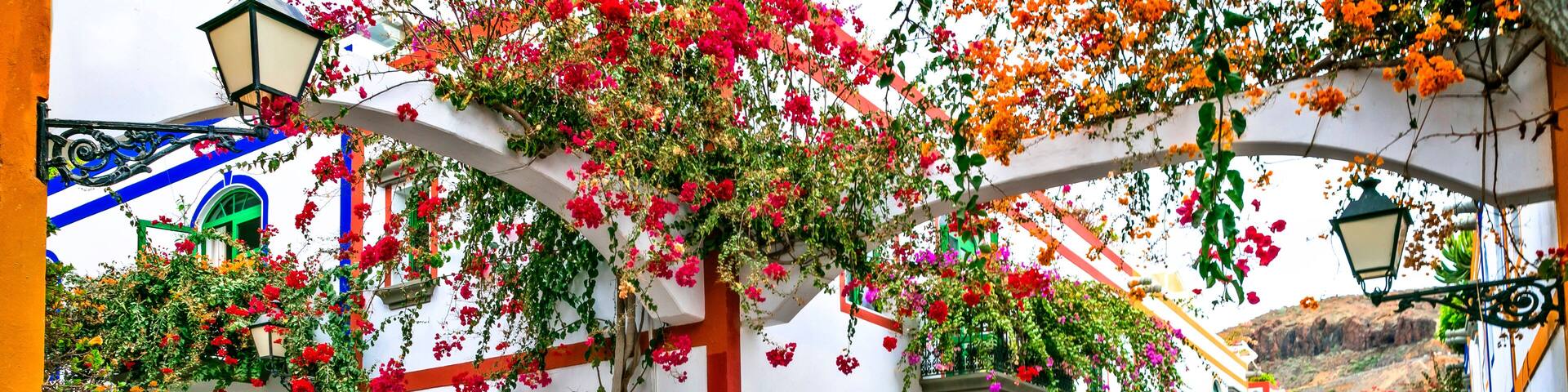 Puerto de Mogan Gran Canaria Spain symmetrical floral arches with bougainvillea flowers and white houses no people traditional street architecture for wall art print and travel interior decor