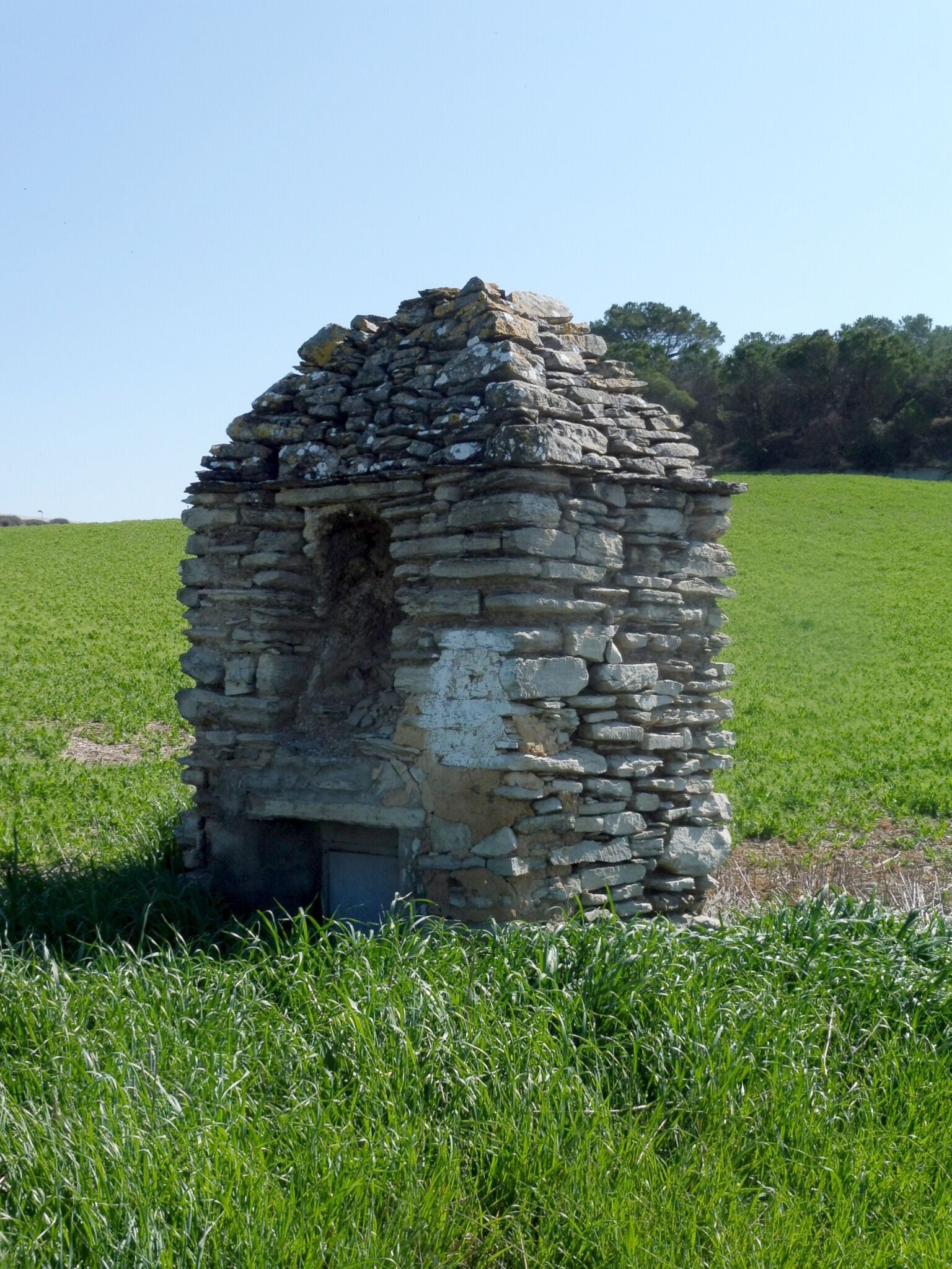 A stone structure in a grassy field.