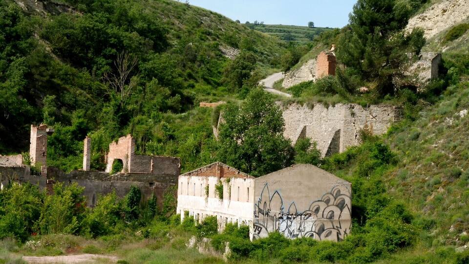 A hillside with ruins, graffiti, and a path.