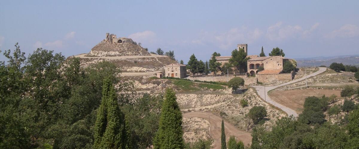 A historical site with ruins, a hilltop structure, and a building with arches.