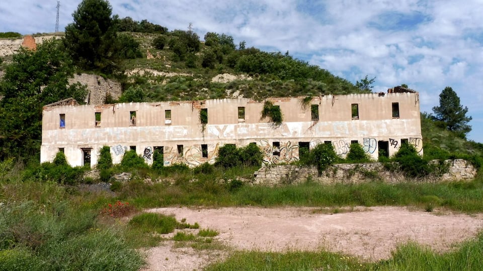 An abandoned building with graffiti on a hillside.