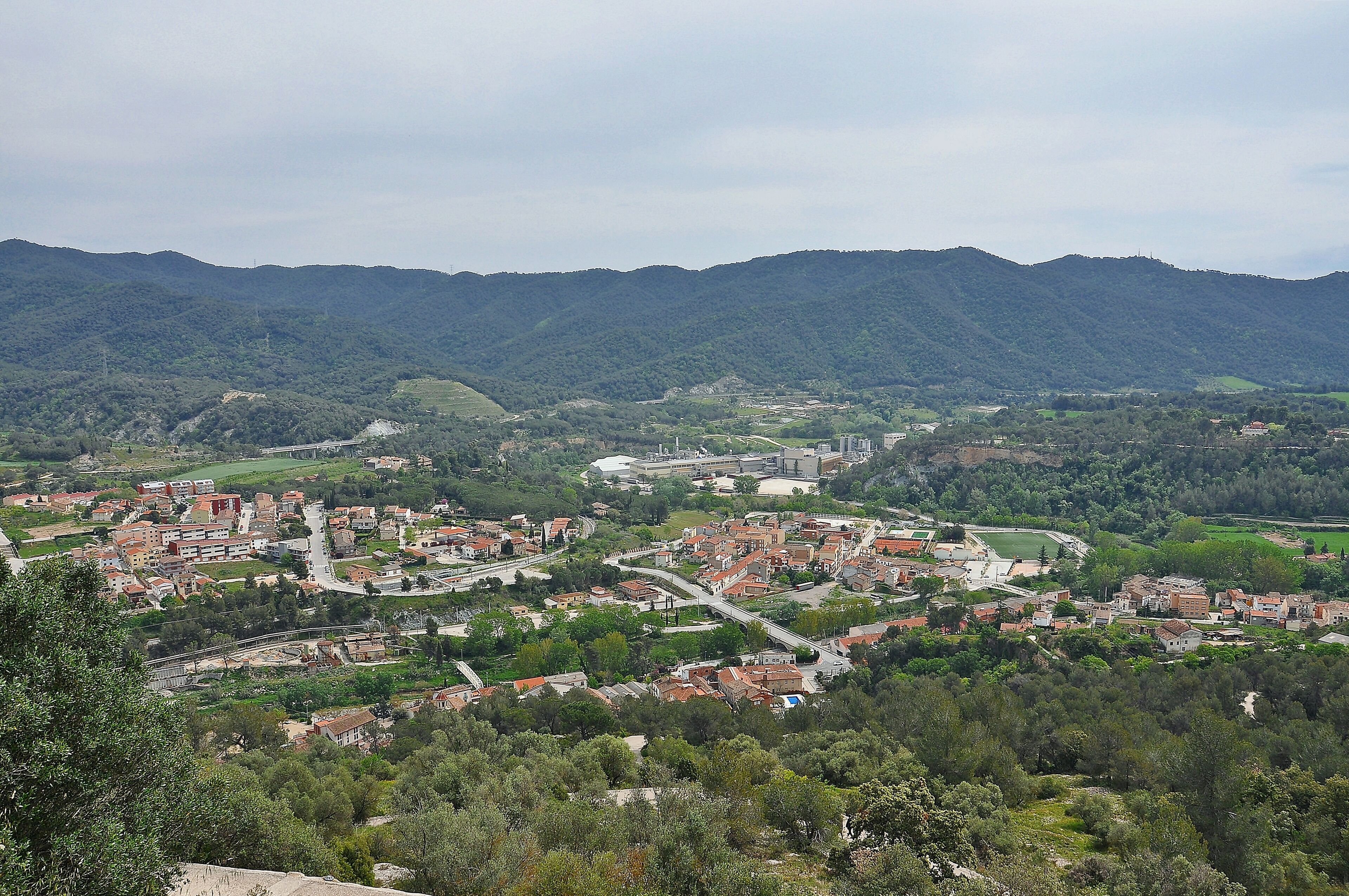 A town nestled in a valley with a river running through it, surrounded by mountains.
