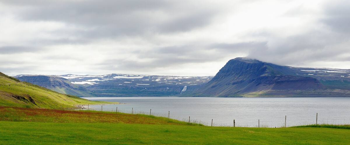 A mountainous landscape with a lake and a grassy foreground.