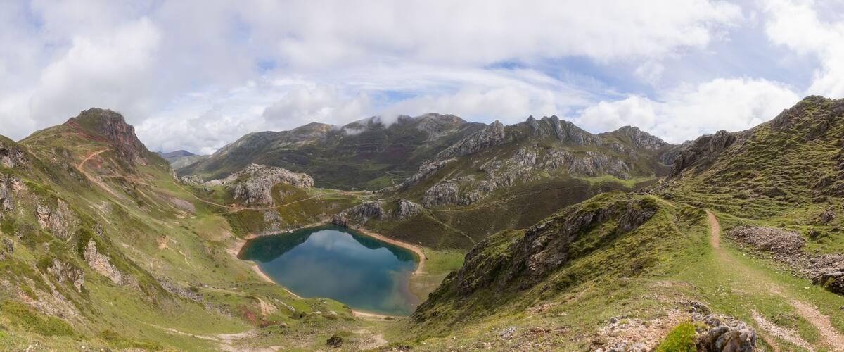 A mountain landscape with a lake surrounded by rocky terrain and a winding path.