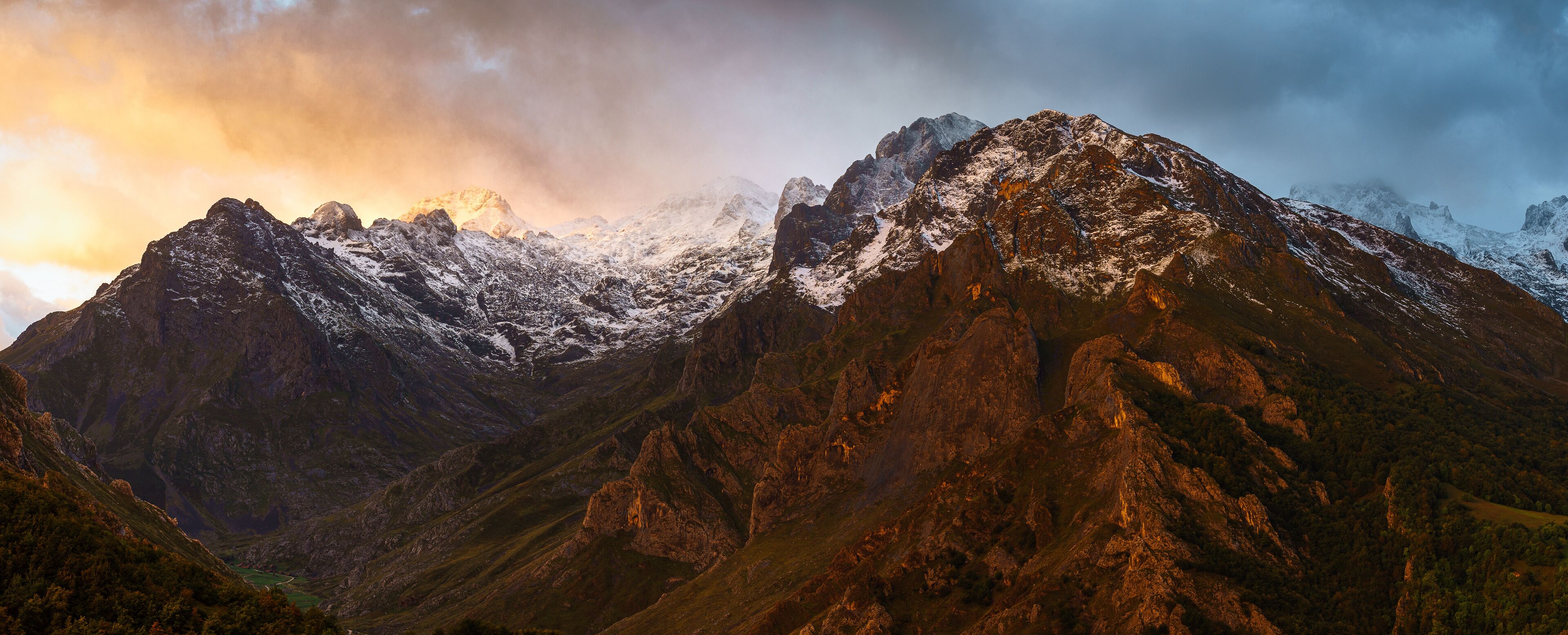 A rugged mountain range with snow-capped peaks and a valley.