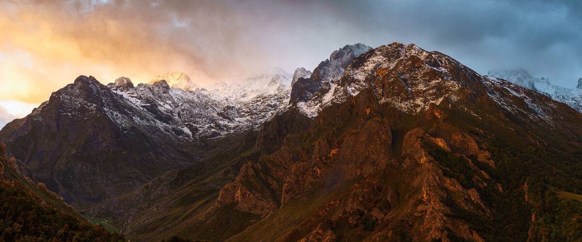 A rugged mountain range with snow-capped peaks and a valley.