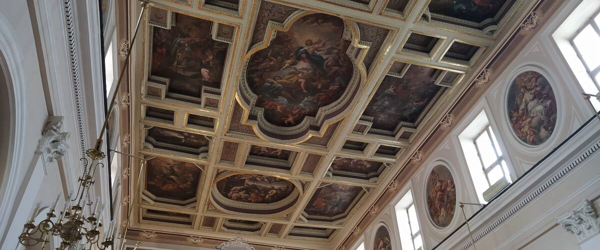 An ornate ceiling with intricate frescoes and a chandelier.