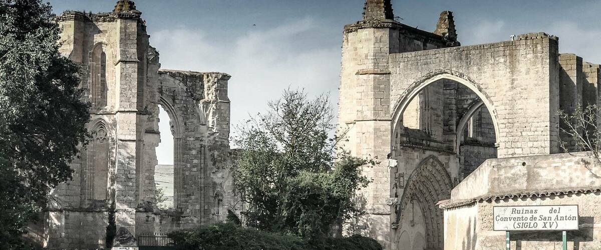 The ruins of the Convento de San Anton (Siglo XV) with a road leading through the entrance.