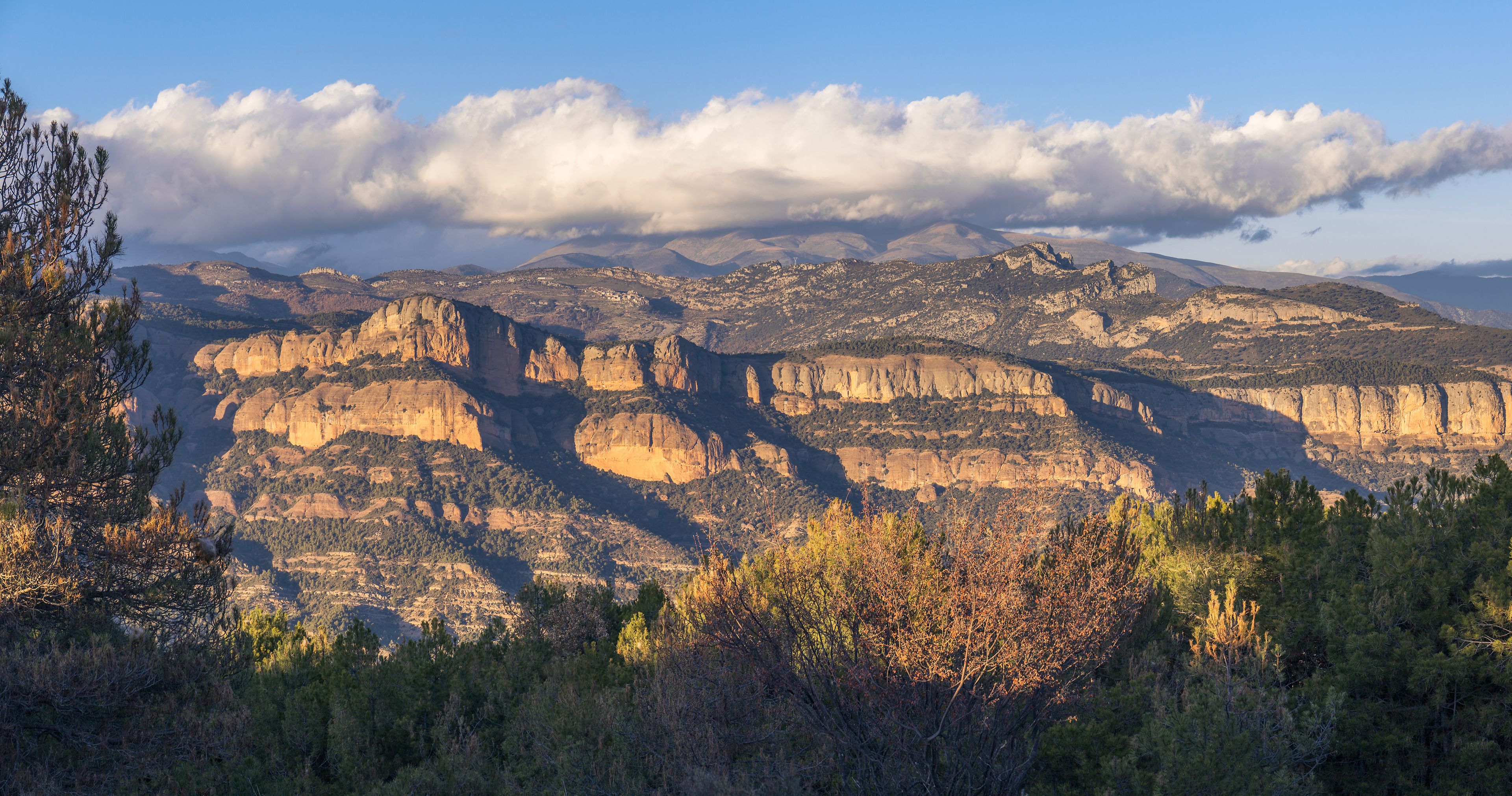 Paisagem montanhosa com formações rochosas sobrepostas e céu claro.