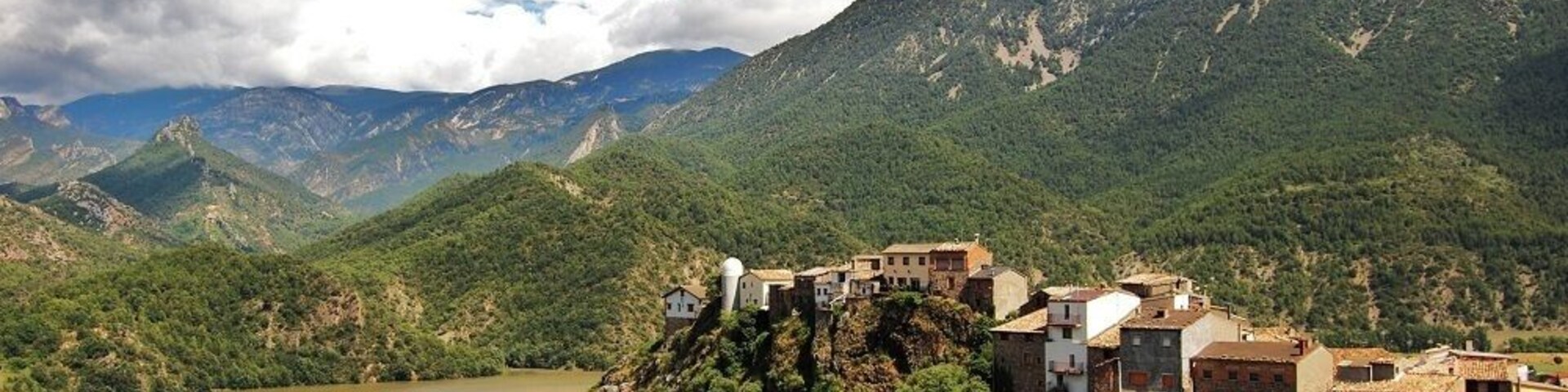 Un paisaje montañoso con un pueblo en la cima de una colina, dominando un río.