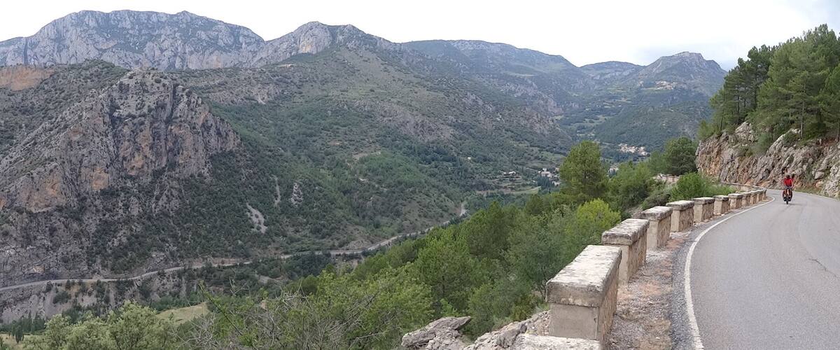 A mountainous landscape with a winding road and a guardrail.
