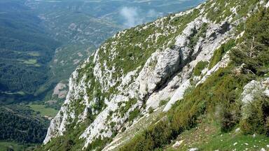 A mountainous landscape with rocky slopes and patches of greenery.