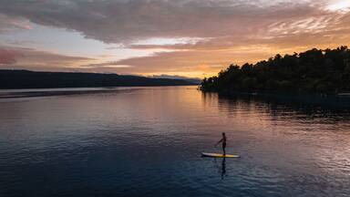 Una persona che fa paddleboard su un lago calmo al tramonto.
