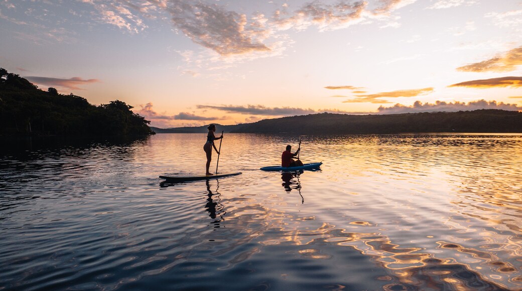A sunset over a calm lake with two paddleboarders.