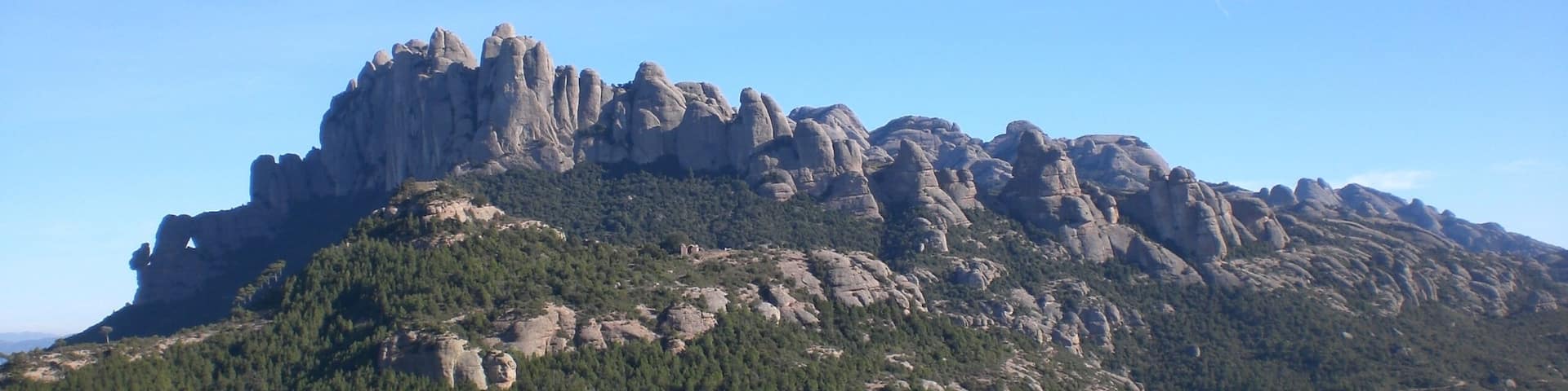 A rugged mountain with prominent rock formations and dense forest.