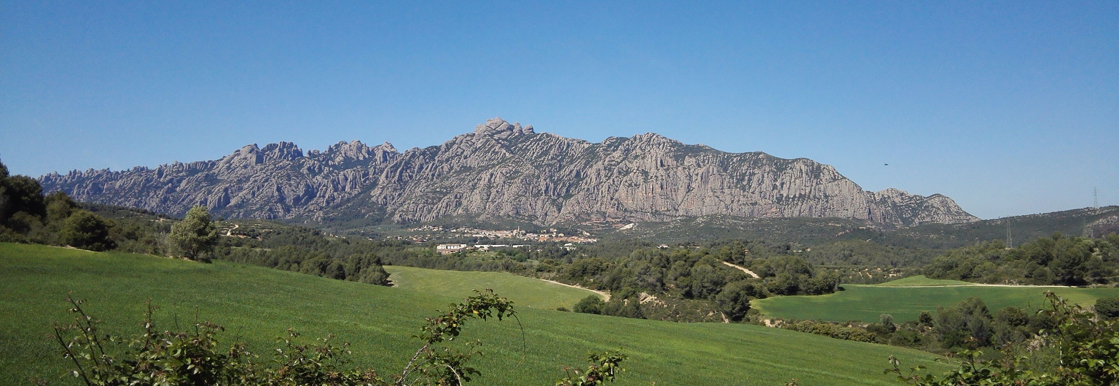 A mountainous landscape with green fields and a village in the valley.