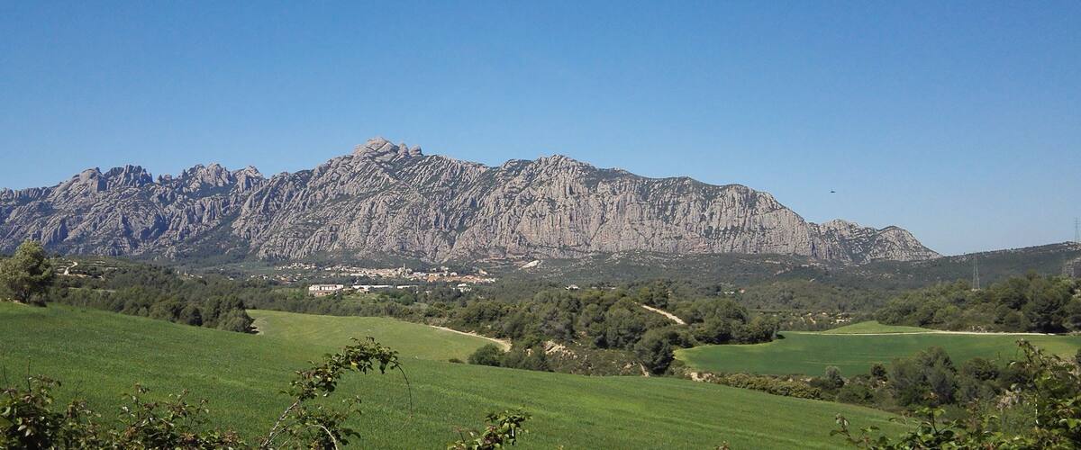 A mountainous landscape with green fields and a village in the valley.