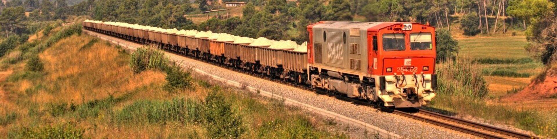 A train on tracks with a mountainous landscape in the background.