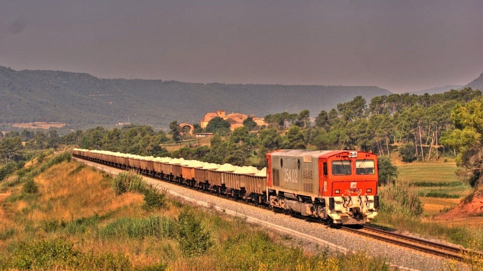 A train on tracks with a mountainous landscape in the background.