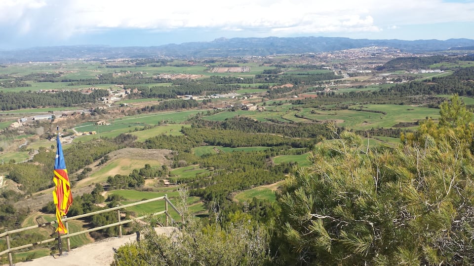 A panoramic view of a rural landscape with rolling hills, fields, and scattered buildings.