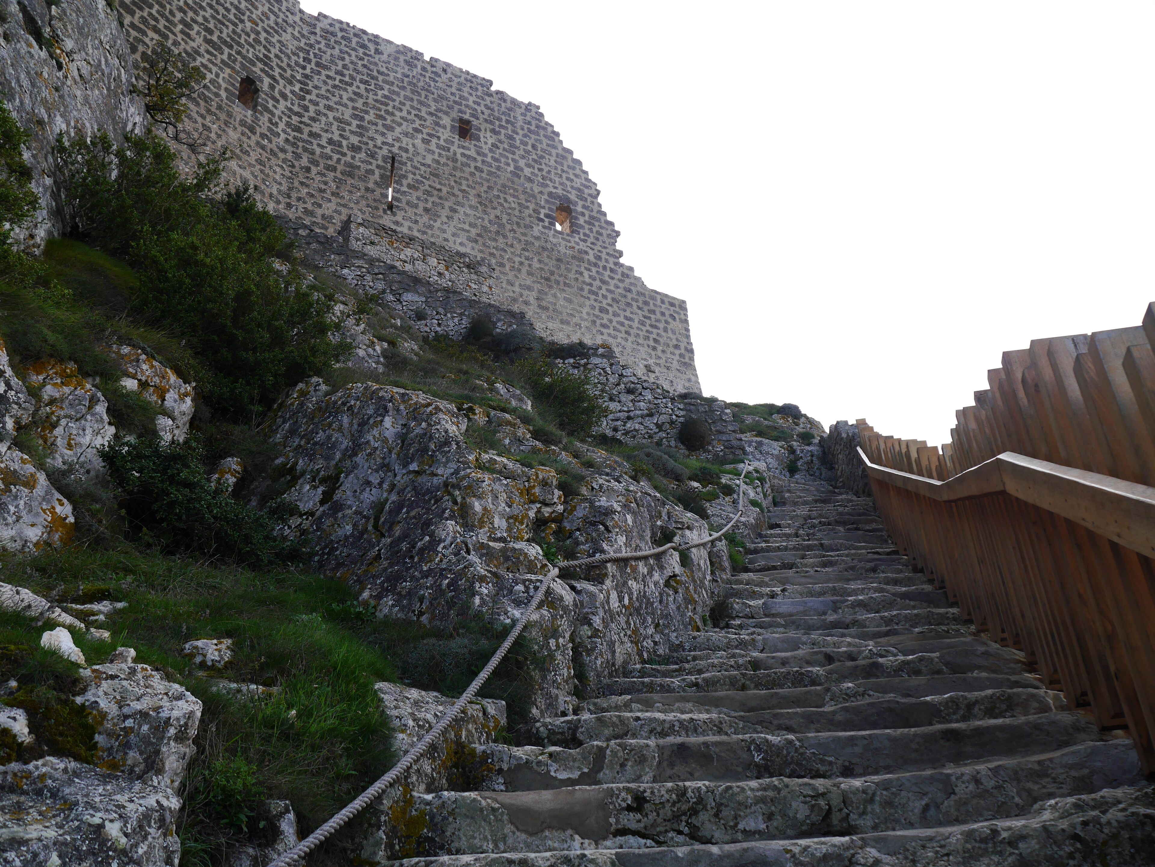 A stone staircase leading up a rocky hill with a stone wall in the background.
