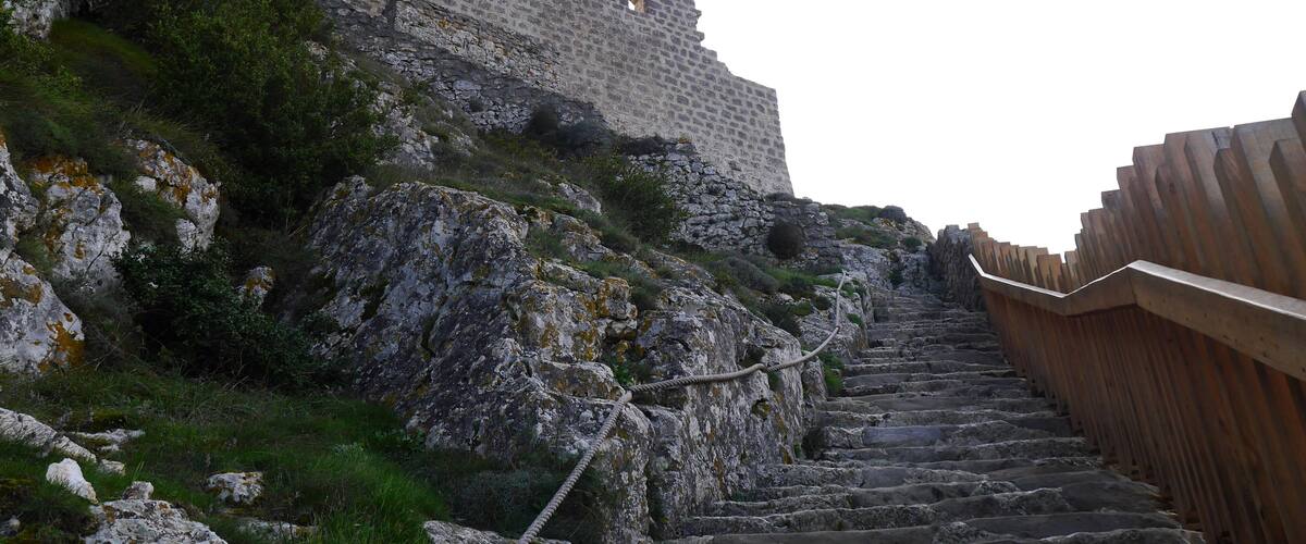 A stone staircase leading up a rocky hill with a stone wall in the background.