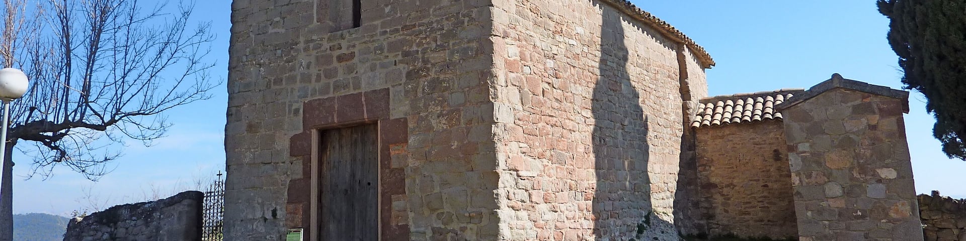 An old stone church with a bell tower and a small adjacent building.